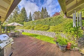 Eine Holzterrasse mit Grill, Gartenmöbeln und Topfpflanzen.