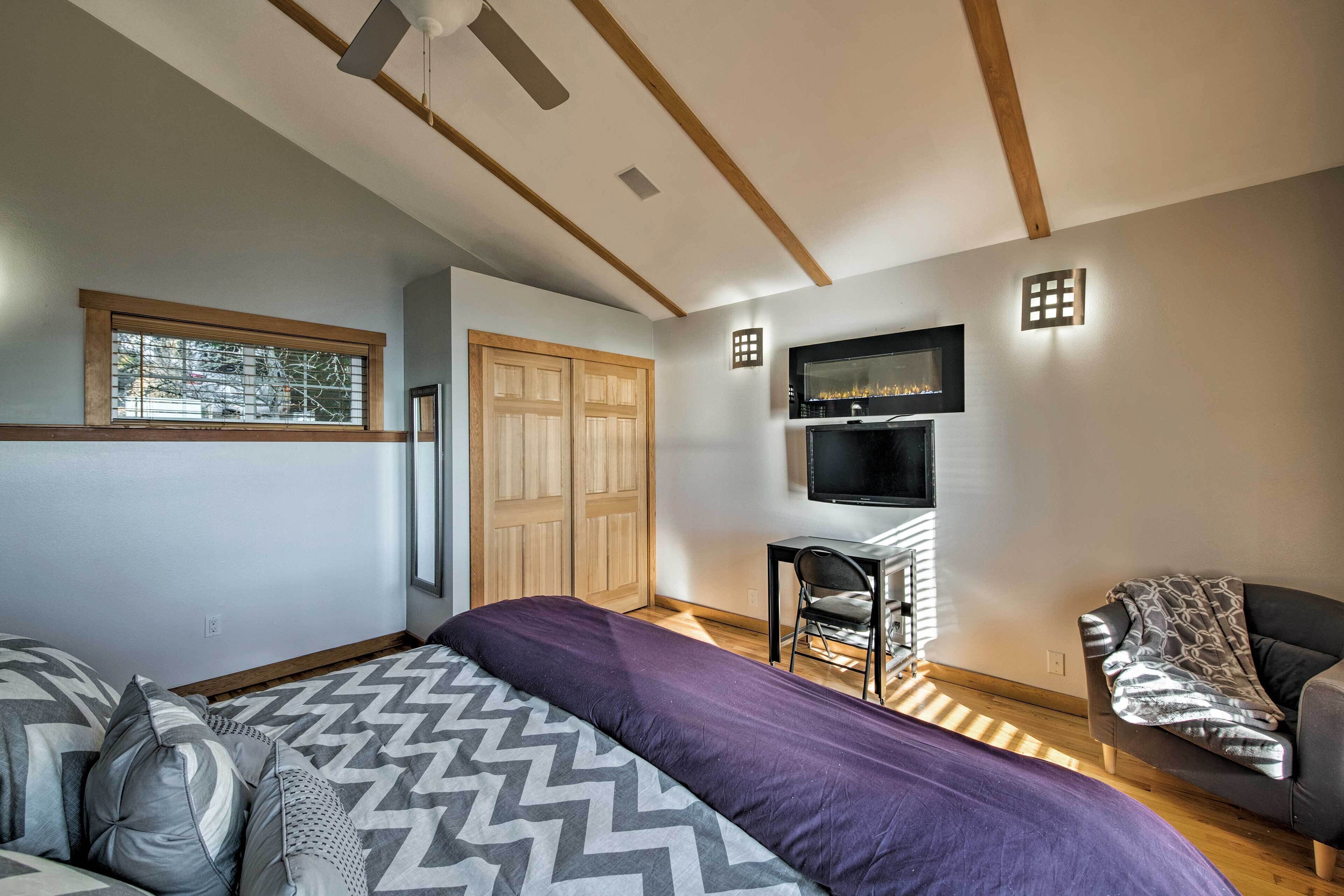 Un dormitorio moderno con cama, escritorio, silla, televisor y armario.