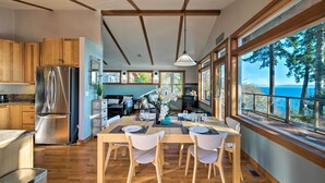 Una cocina moderna con armarios de madera, un refrigerador de acero inoxidable y una zona de comedor con una mesa y sillas de madera.