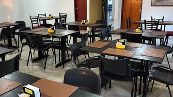 Un espace repas comprenant plusieurs tables et chaises, dont certaines sont accompagnées de menus et de condiments.