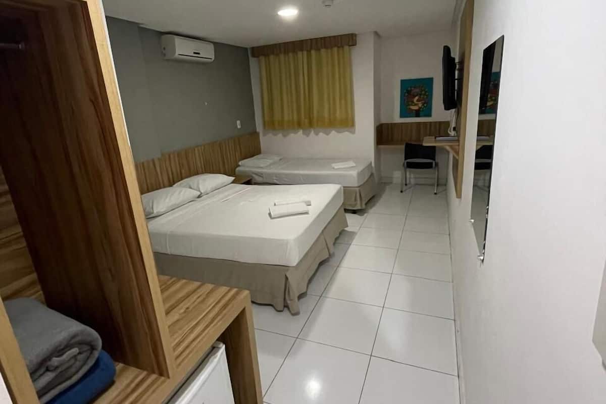 Une chambre d’hôtel avec deux lits, un bureau et un petit réfrigérateur.