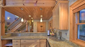 Una cocina con encimeras de granito, armarios de madera y un lavamanos de acero inoxidable.