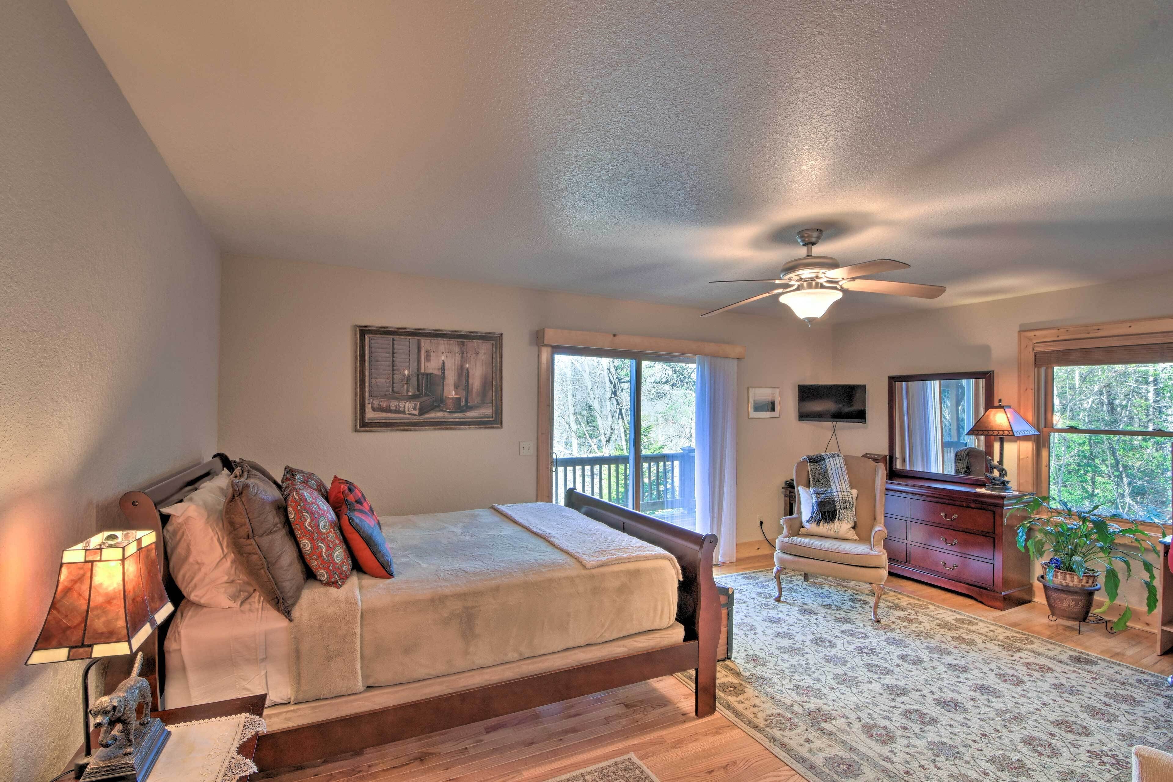 A bedroom with a bed, a ceiling fan, a dresser, a chair, and a window.