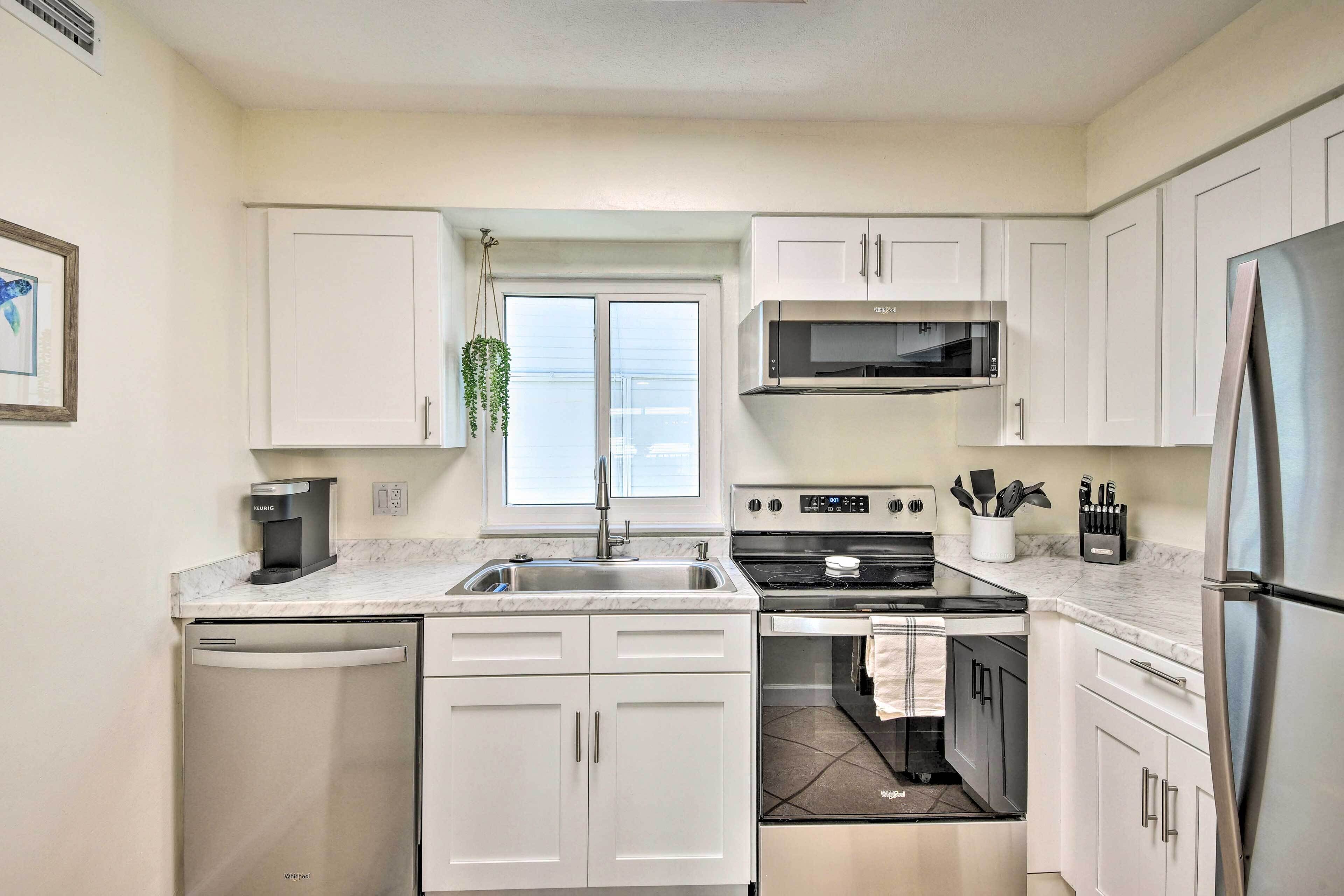 A modern kitchen with white cabinets, a stainless steel refrigerator, a built-in oven, and a microwave.