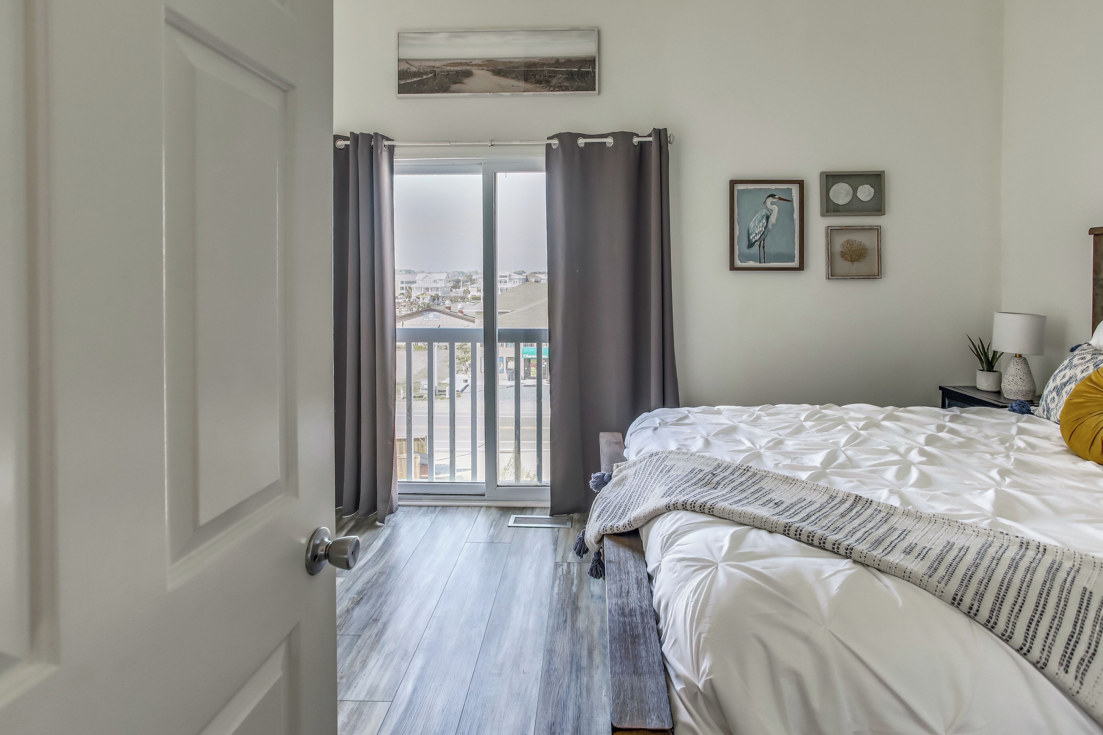 A bedroom with a bed, a nightstand, a lamp, and a view of the outside through a sliding door.