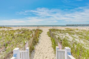A beach path leading to the ocean with a pier in the distance. - 'salt & Light' Oceanfront Condo w/ Pool & Elevator (Ocean Isle Beach)