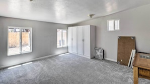 Ein geräumiger Raum mit großem Fenster, Deckenventilator und Holztisch.