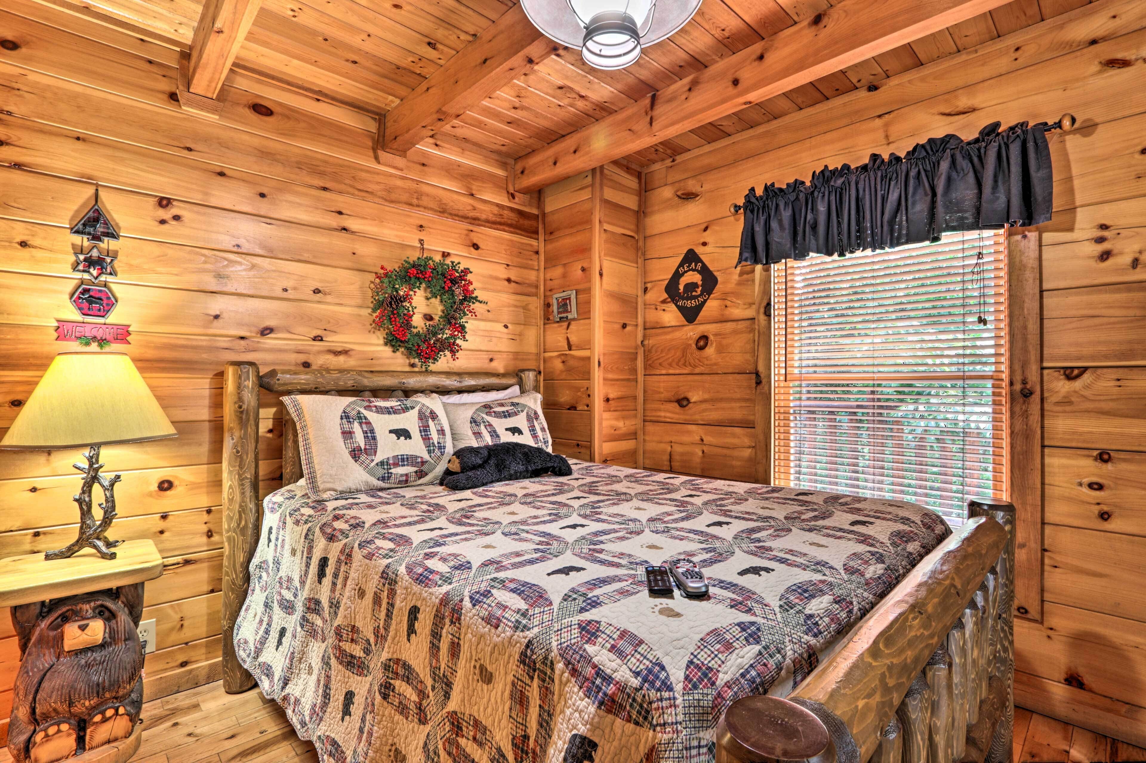 Une chambre dans une cabane en bois, avec un lit, une lampe, un animal en peluche, un élément de décoration murale et une fenêtre avec des stores.