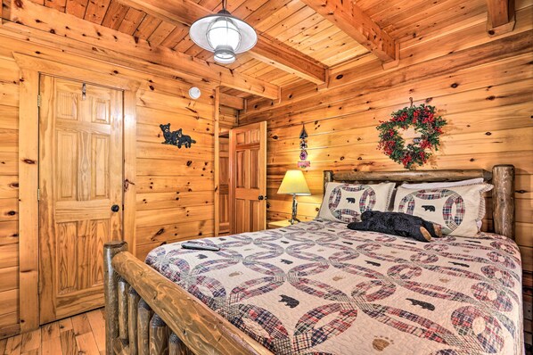 Habitación de una cabaña de madera con una cama, una mesita de noche, una lámpara y un arreglo de guirnaldas en la pared.