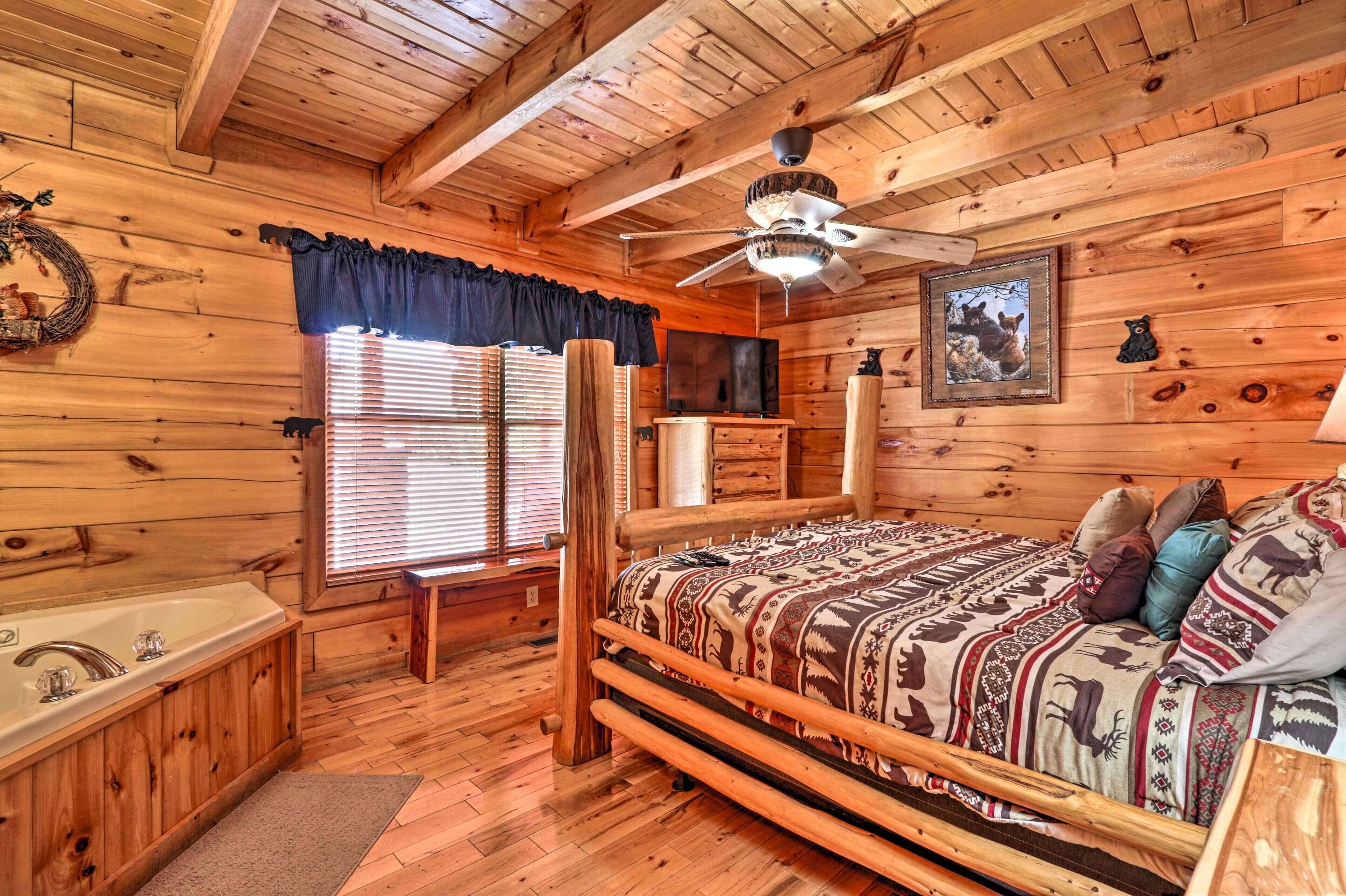 Un dormitorio de cabaña rústica con una cama de madera, ventilador de techo, ventana con persianas y una bañera de madera.