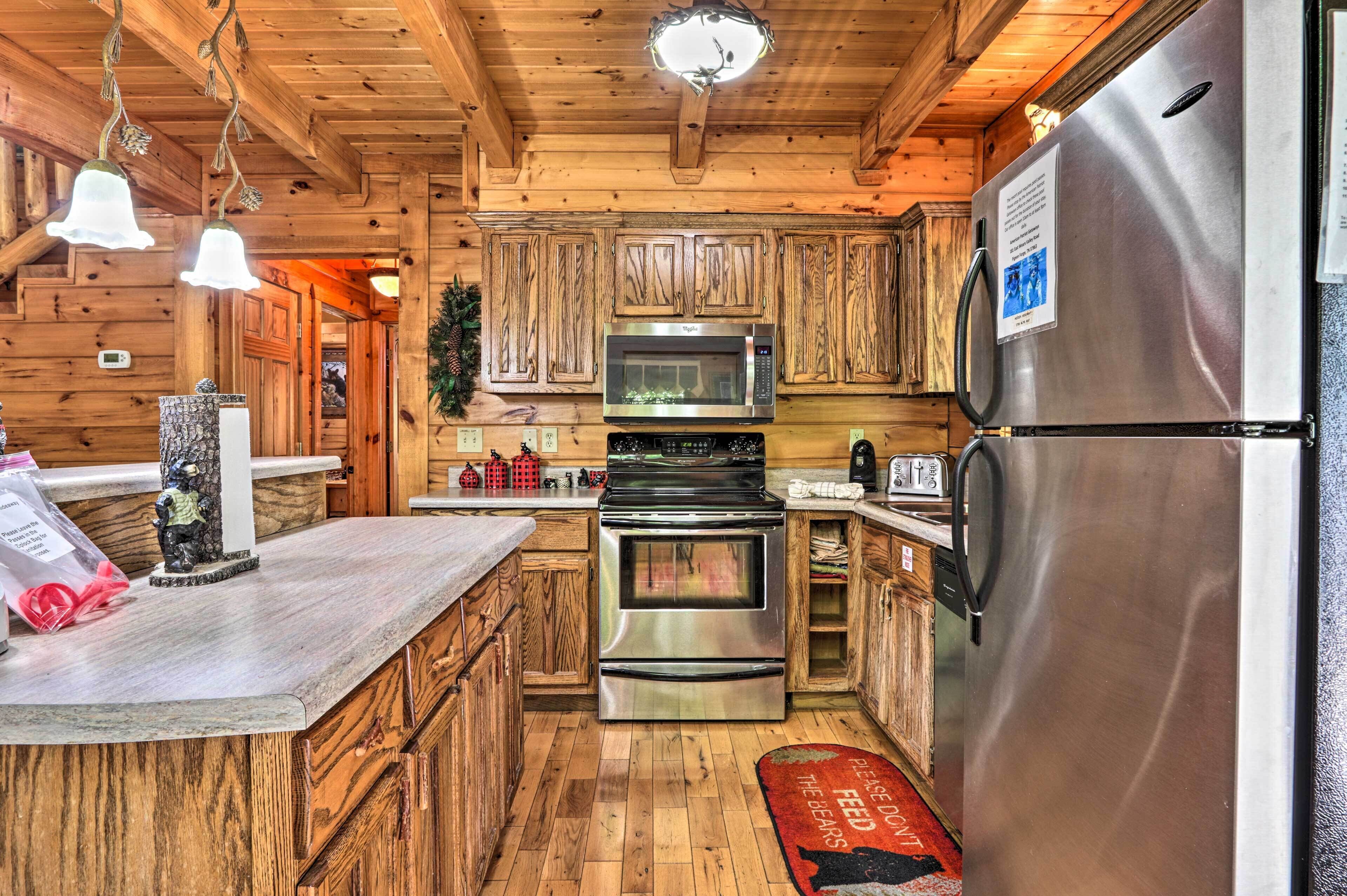 Une cuisine rustique, située dans une cabane en bois, équipée d’un réfrigérateur en acier inoxydable, de deux fours, d’un four à micro-ondes et de meubles de rangement en bois.