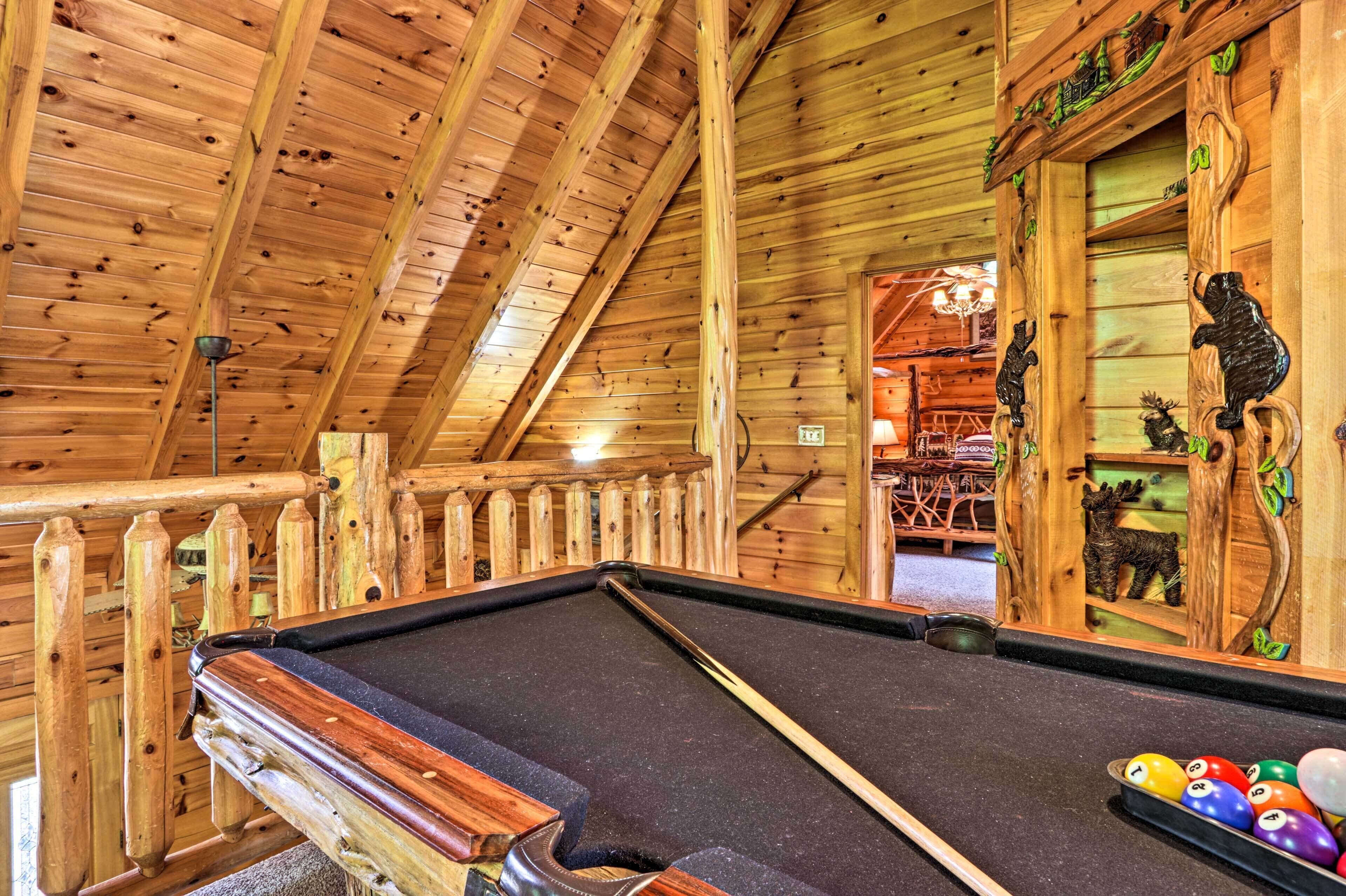 Interior de madera con mesa de billar, vigas de madera y una puerta con tallas de animales.