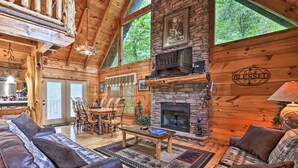 Un intérieur chaleureux de chalet en bois avec une cheminée en pierre, des meubles en bois et de grandes fenêtres.