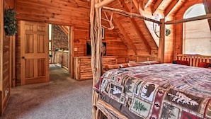 Une chambre dans une cabane en rondins, avec un lit à baldaquin, des murs en bois et une cheminée en pierre.