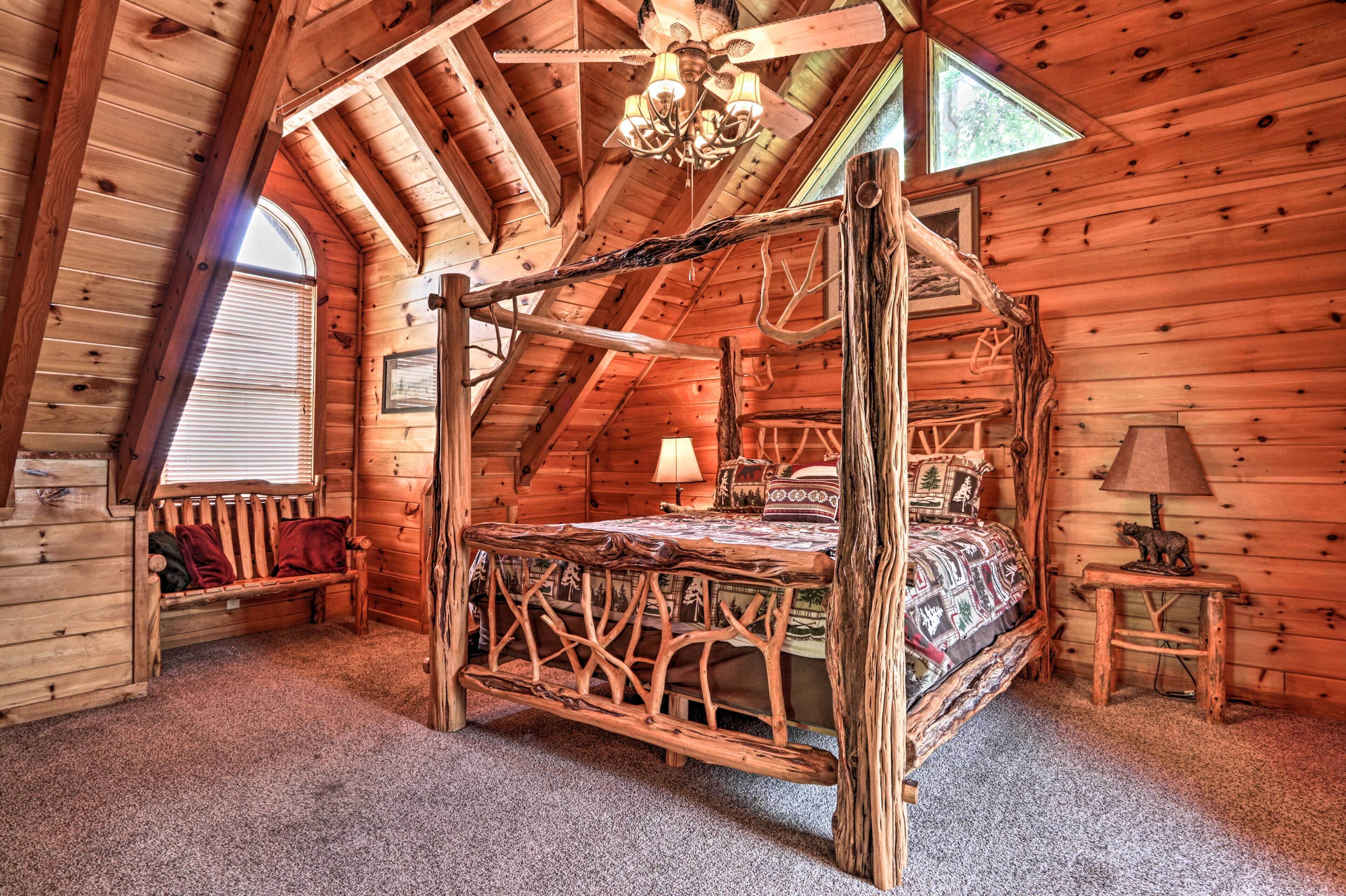 Ein Schlafzimmer in einer Blockhütte mit einem Himmelbett, einer hölzernen Bank, einem kleinen Tisch und einer Kandelaberleuchte.