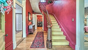 A staircase with a red wall and a wooden handrail leading to a second floor.