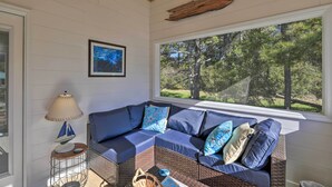 A cozy room with a sectional sofa, a lamp, and a window with a view of trees. - Beaufort Pad w/ Patio: 3 Blocks to Waterfront! (Beaufort)