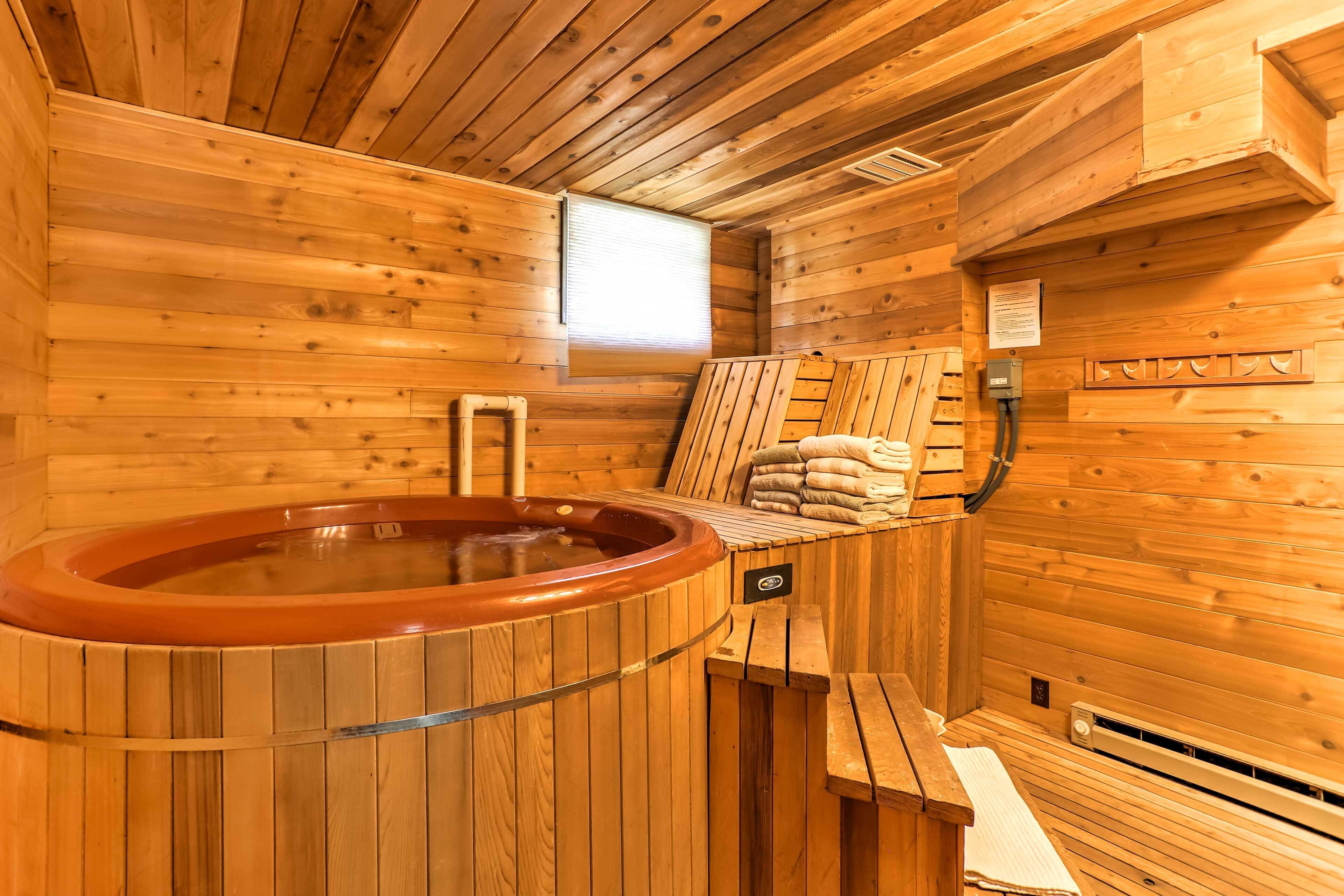 A wooden sauna with a hot tub, benches, and towels.