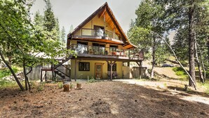 Une cabane en rondins à deux étages, dotée d’un balcon, entourée d’arbres et surplombant un ciel dégagé.