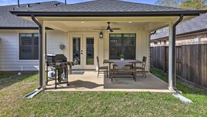A covered patio with a grill, table, and chairs. - Well-appointed Montgomery Home w/ Fenced Yard (Montgomery)