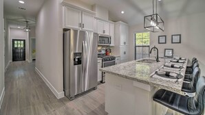 A modern kitchen with stainless steel appliances, a granite countertop, and a dining area with black chairs. - Well-appointed Montgomery Home w/ Fenced Yard (Montgomery)