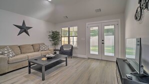 A living room with a sofa, coffee table, TV, and a star decoration on the wall. - Well-appointed Montgomery Home w/ Fenced Yard (Montgomery)