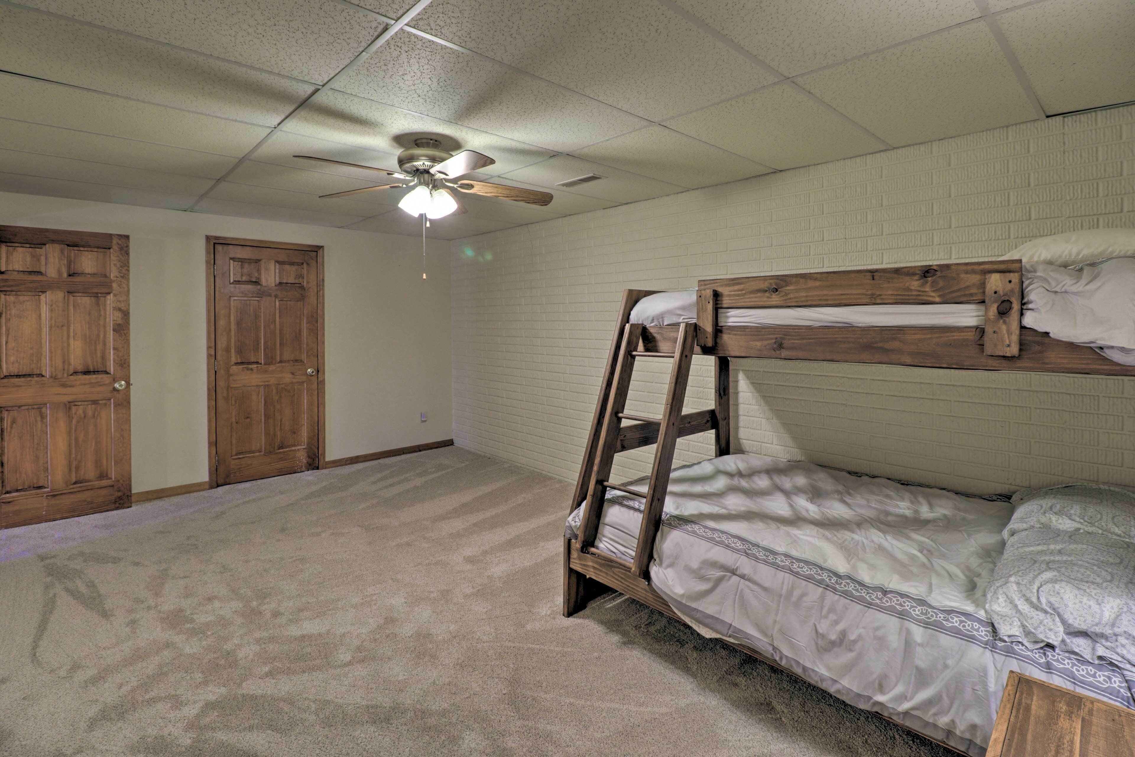 A room with a bunk bed, a ceiling fan, and two wooden doors.