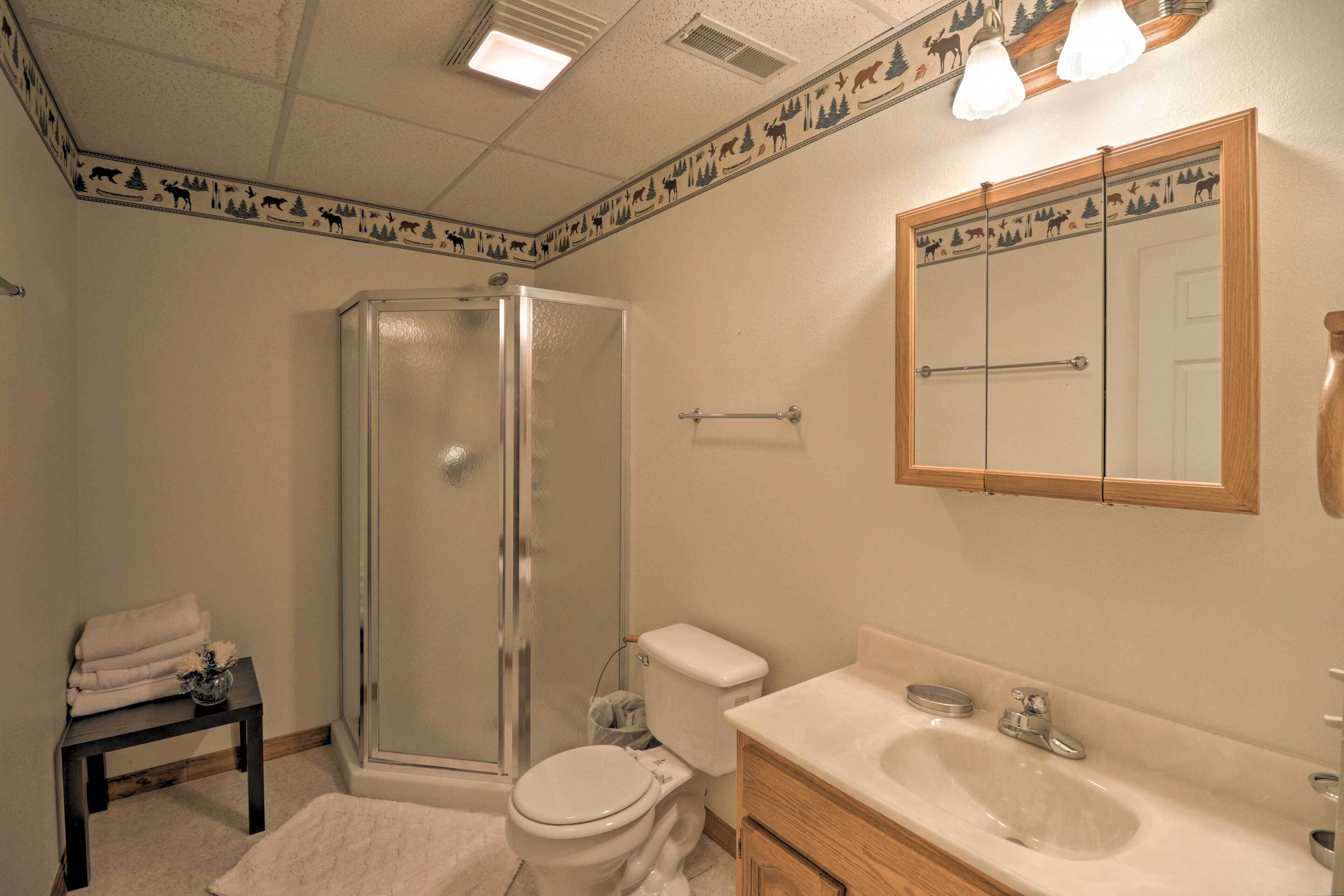 A bathroom with a shower, toilet, sink, and a mirror.
