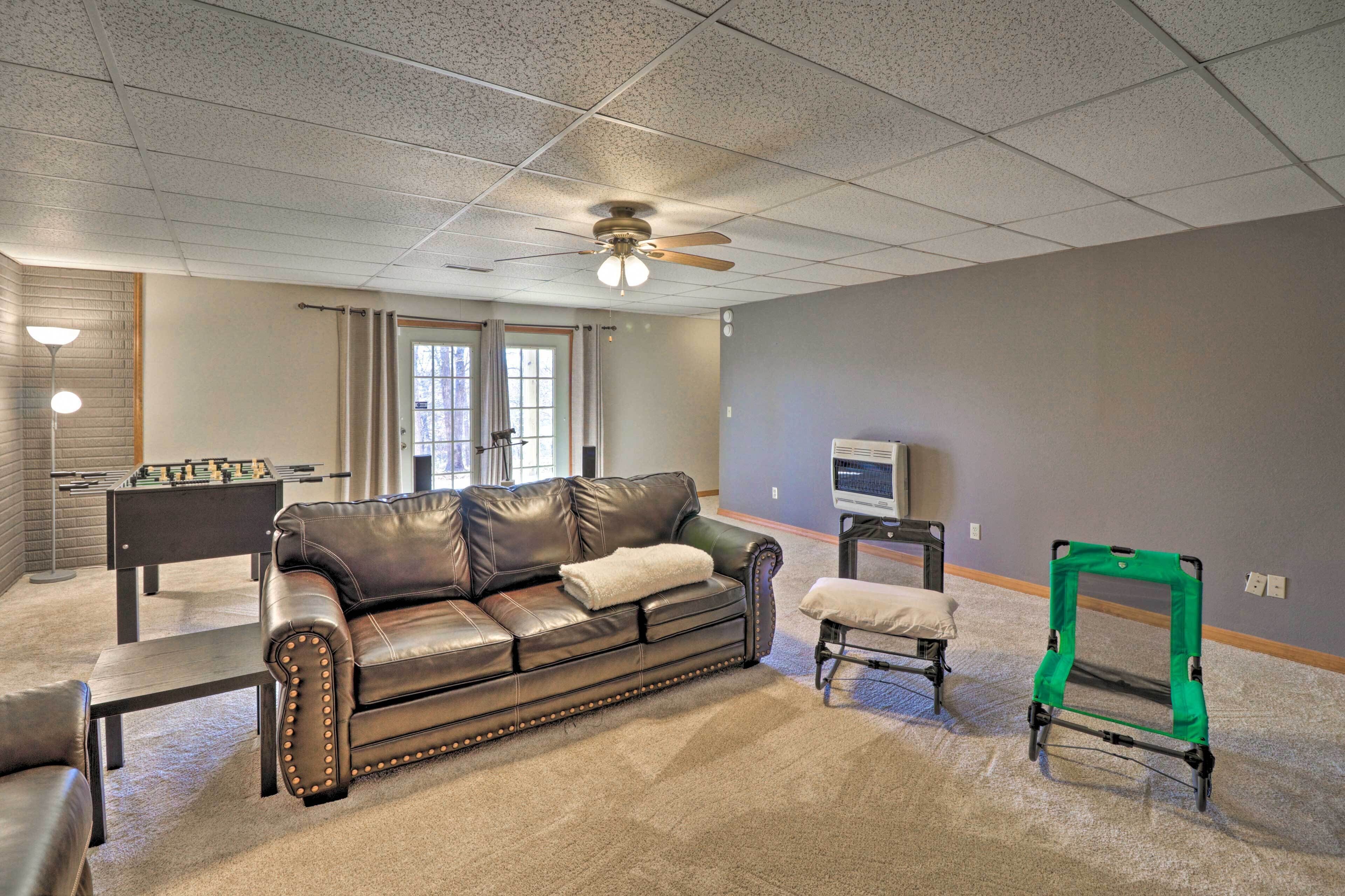 A living room with a leather sofa, a foosball table, a green walker, and a television.