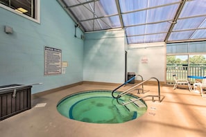 Piscina interior com teto de vidro, aviso de segurança e escada de acesso.