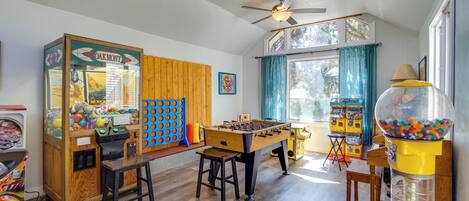 A room with a foosball table, a vending machine, and a window with curtains.