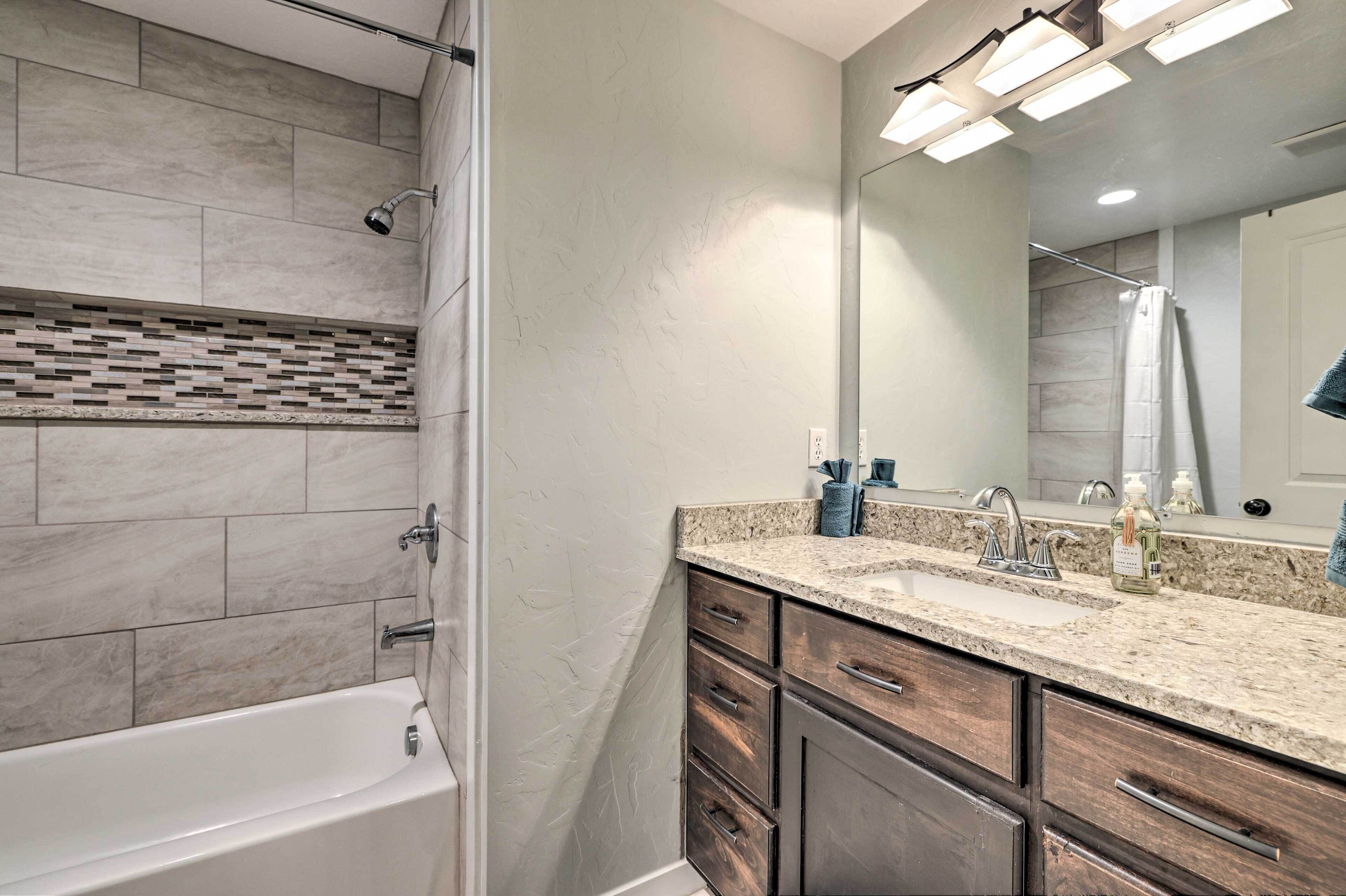 Un baño moderno con bañera, tocador con espejo y zona de ducha.