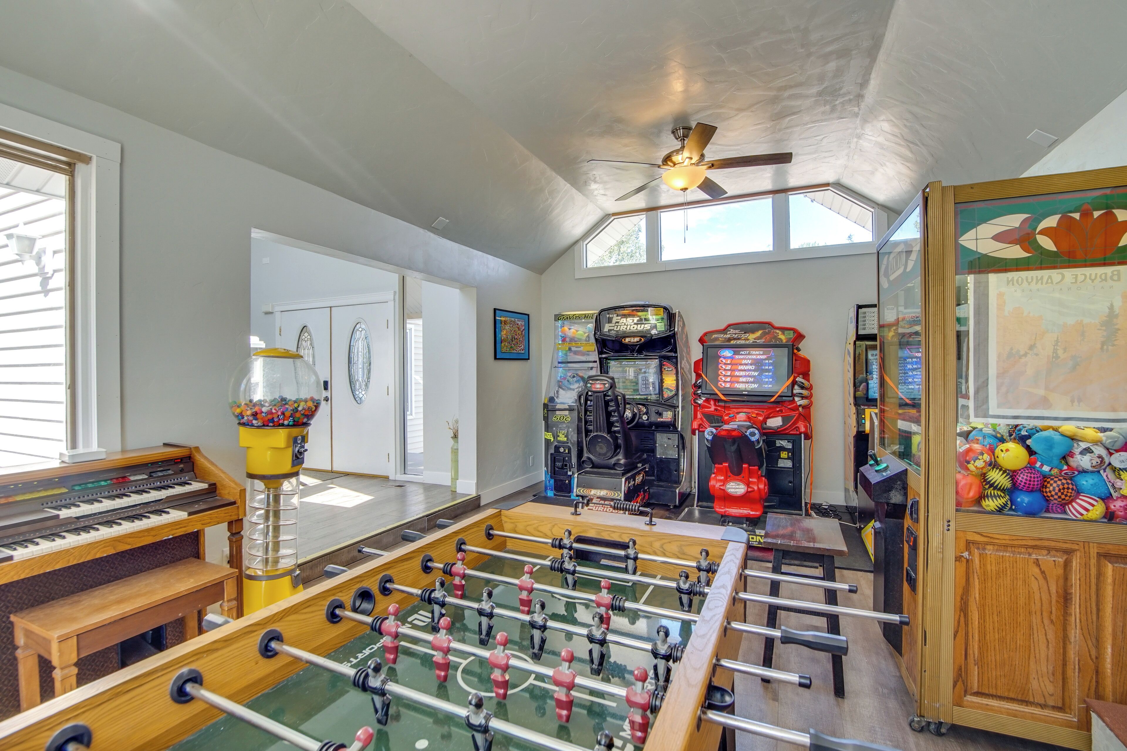 Um quarto com mesa de pebolim, piano, jogos de fliperama e máquina de vendas.