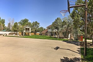A residential driveway with a basketball hoop, houses, and trees. - Hike, Play & Relax: Cedar City Group Getaway (Cedar City)