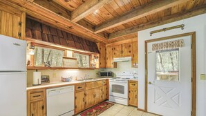 Una cucina con mobili in legno, un frigorifero bianco, una lavastoviglie, un fornello e un forno a microonde.