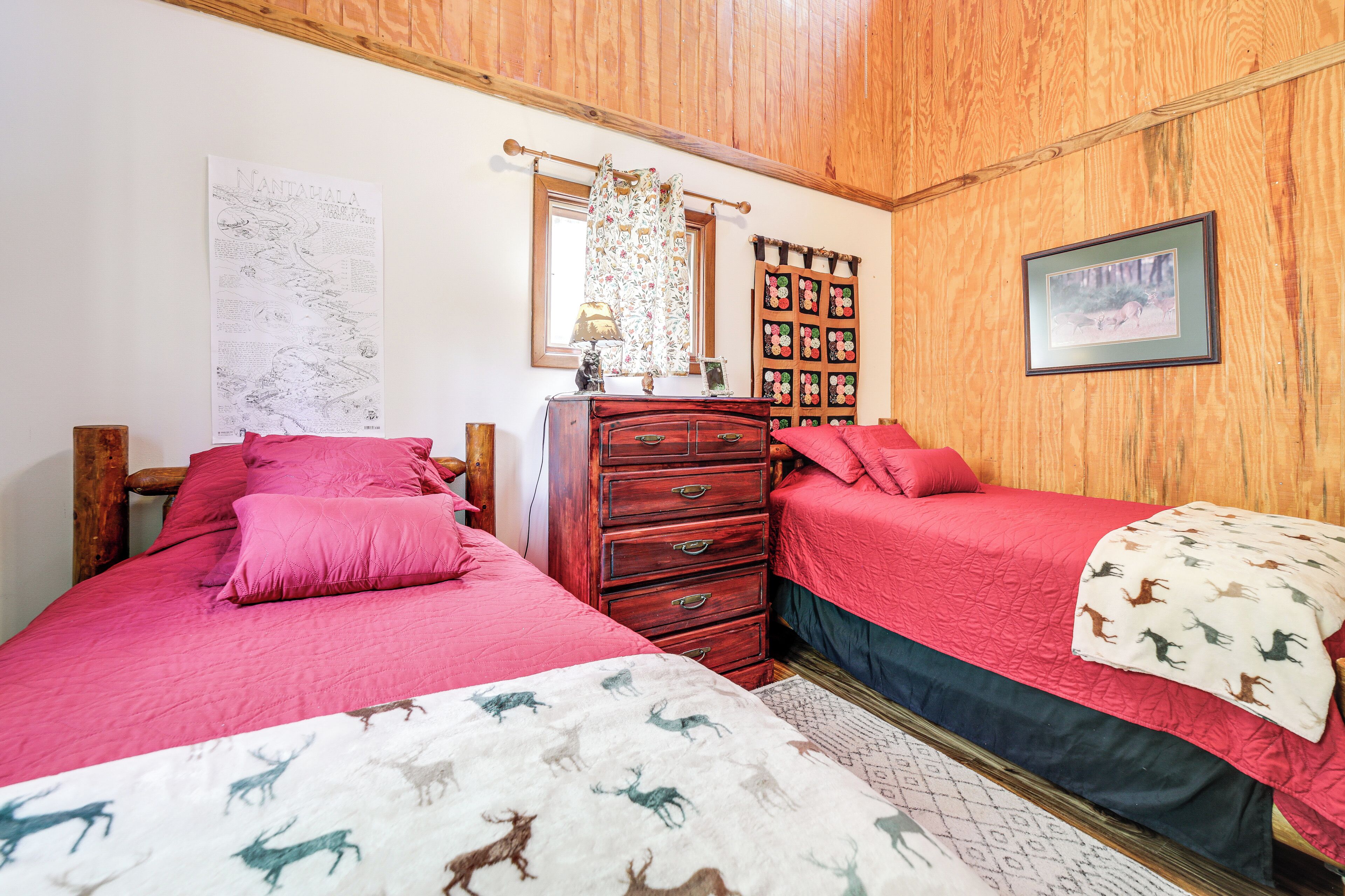 Un dormitorio con dos camas, paredes de madera, un aparador y un mapa colgado en la pared, junto con un cuadro enmarco.