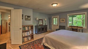 Una camera da letto con un letto grande, una libreria, una scrivania e una finestra vista alberi.