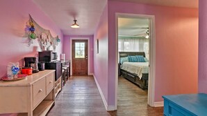 A narrow hallway with a kitchenette on the left, leading to a bedroom with a bed and a nightstand. - Bayfront Deck: 'casa Pescadores' Rockport Escape (Rockport)