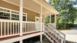 A covered porch with a wooden deck, a staircase, and a sign that reads "Welcome to Lake House." - Modern Tims Ford Lake Home w/ Private Dock & Pool! (Lynchburg)