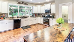 A spacious kitchen with white cabinets, a large island, and a view of the outdoors through the windows. - Modern Tims Ford Lake Home w/ Private Dock & Pool! (Lynchburg)