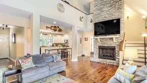 A spacious living room with a fireplace, a kitchen in the background, and a dining area. - Modern Tims Ford Lake Home w/ Private Dock & Pool! (Lynchburg)