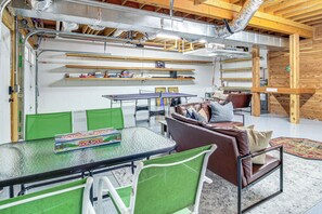 A room with a ping pong table, green chairs, a brown leather couch, and a red rug. - Modern Tims Ford Lake Home w/ Private Dock & Pool! (Lynchburg)