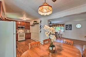 A kitchen with wooden cabinets, a white refrigerator, and a dining area with a wooden table and chairs. - Cute Ellsworth Home w/ Deck, 16 Mi to Acadia! (Ellsworth)