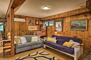 A cozy living room with wooden paneling, two sofas, a patterned rug, and framed artwork on the walls. - Ski Chalet on Saco < 2 Mi To Attitash Resort! (Bartlett)