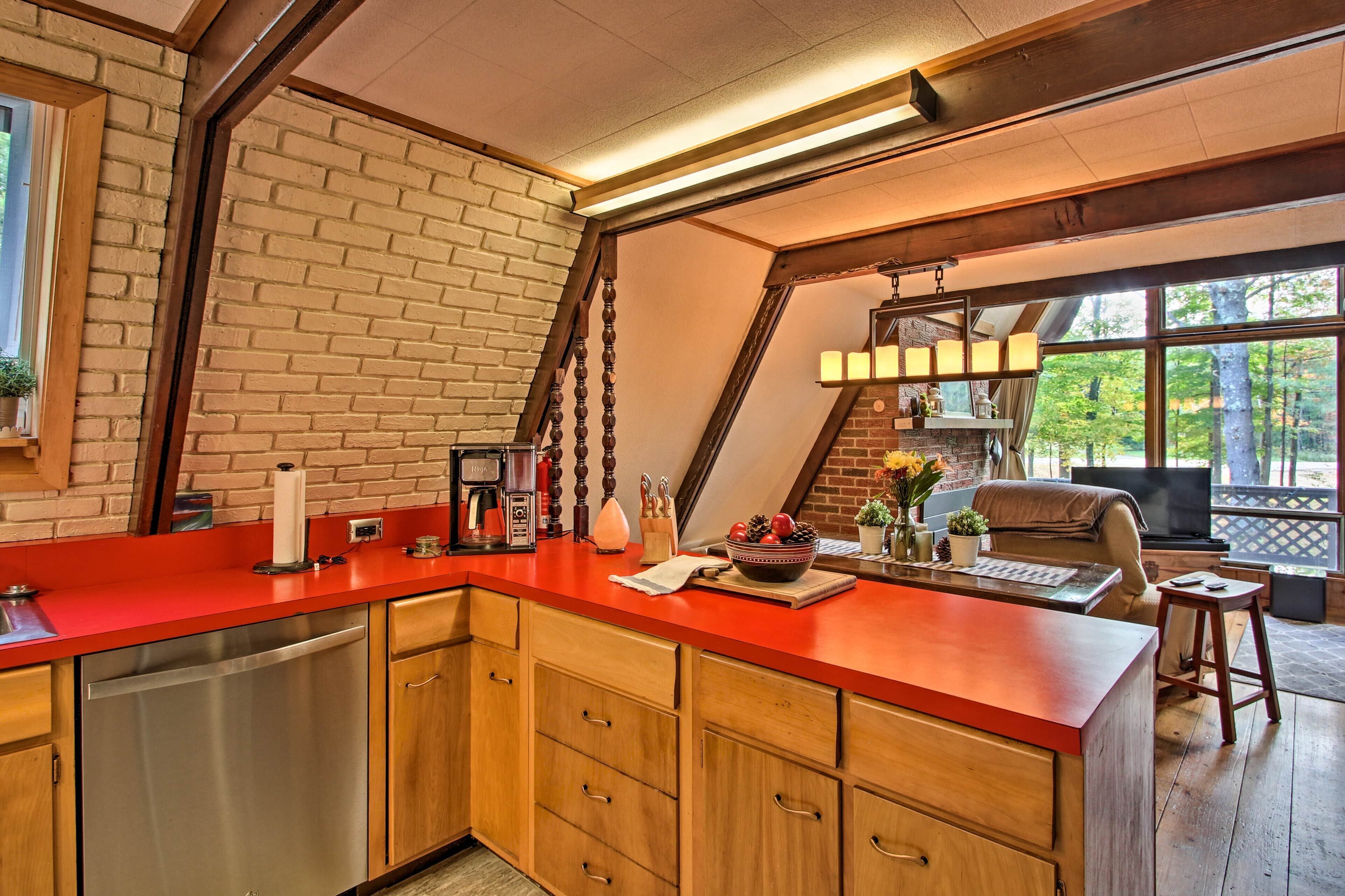 Een keuken met een rode aanrecht, houten kastjes en een bakstenen muur.