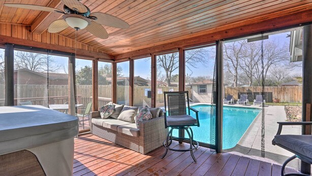 A covered outdoor area with a pool, wooden deck, and seating.