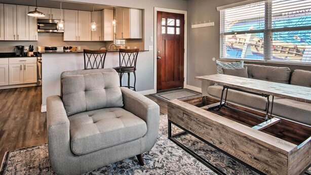 A modern kitchen with white cabinets, a dining area with a wooden table and chairs, and a gray sofa. - Home: Grassy Yard, Walk to Bentonville Square (Bentonville)