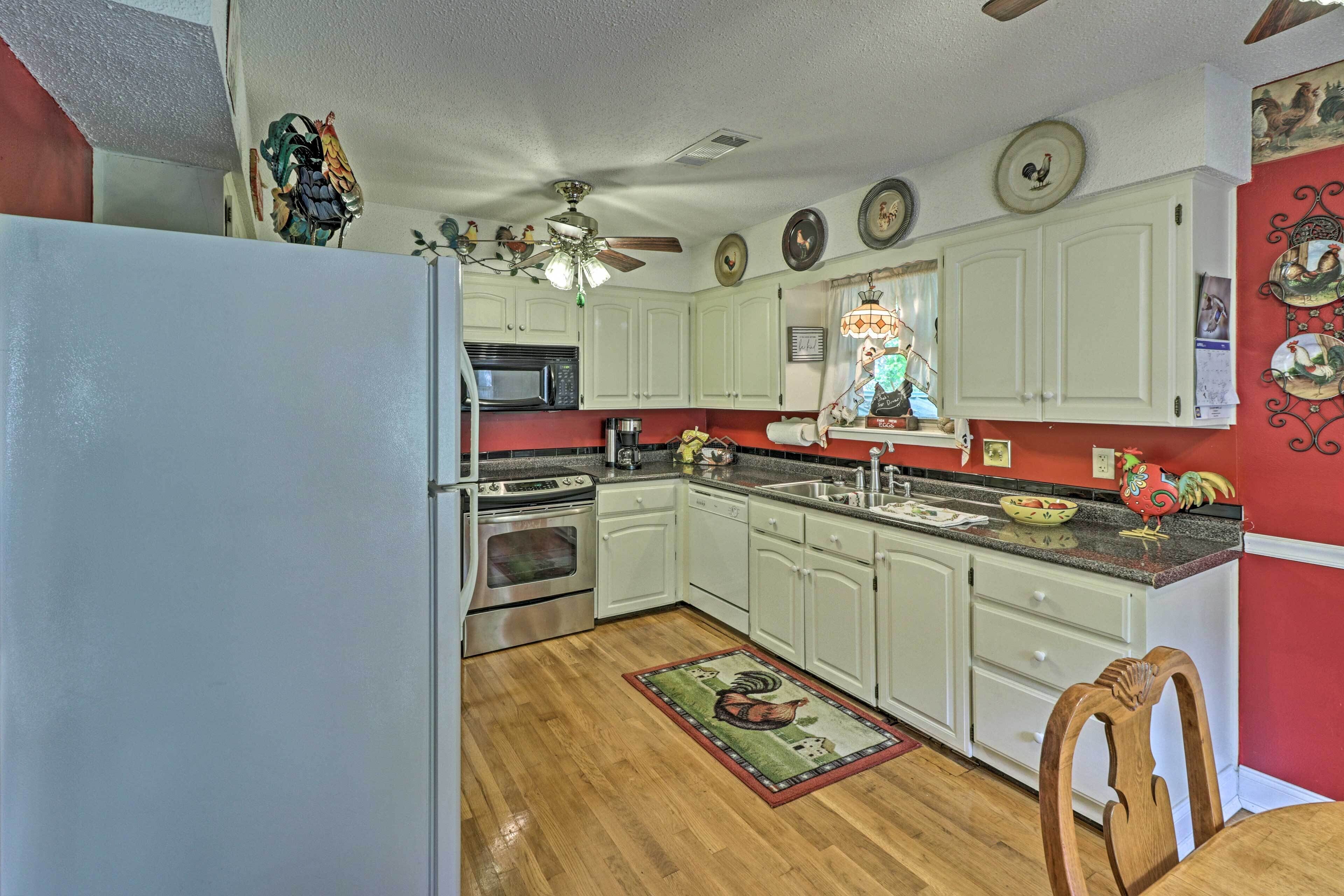 A kitchen with white cabinets, a microwave, an oven, and a ceiling fan.