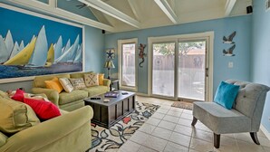 A living room with a large sailboat painting, a green sofa, a gray armchair, and a coffee table.