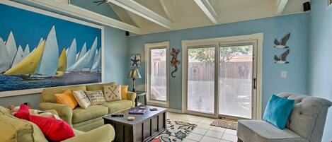 A living room with a large sailboat painting, a green sofa, a gray armchair, and a coffee table.